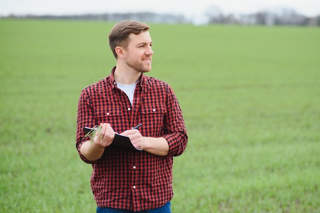 Schöner Bauer Junger Mann, der auf der grünen Wiese spazieren geht Frühlingslandwirtschaft