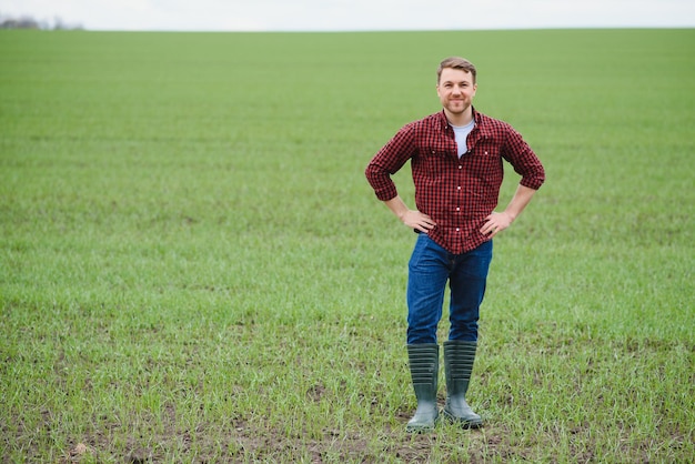 Schöner Bauer Junger Mann, der auf der grünen Wiese spazieren geht Frühlingslandwirtschaft