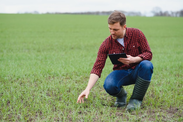 Schöner Bauer Junger Mann, der auf der grünen Wiese spazieren geht Frühlingslandwirtschaft