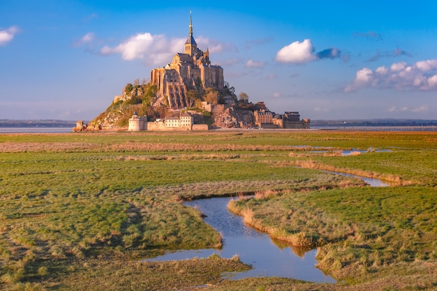 Schöner berühmter Mont Saint Michel bei Sonnenuntergang mit Reflexion im Kanal auf den Wasserwiesen, Normandie, Frankreich