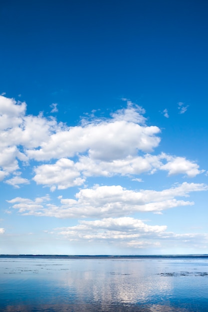 Schöner blauer bewölkter Himmel und seine Reflexion im Wasser des Kaniv-Reservoirs, Ukraine