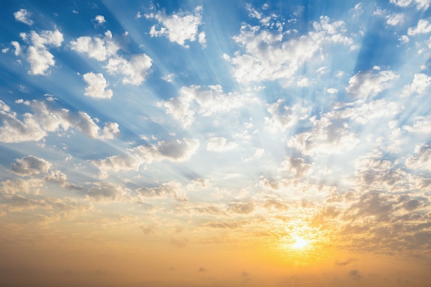 Schöner blauer Himmel mit Wolken, Sonnenuntergang und Sonnenstrahlen