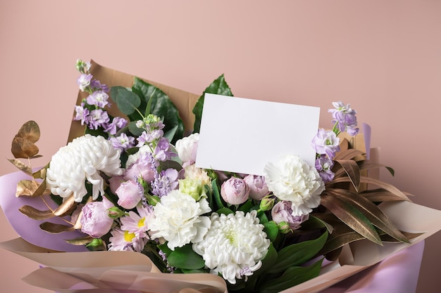 Schöner Blumenstrauß aus gemischten Blumen auf farbigem Hintergrund mit leerer Papierkarte