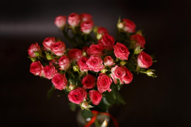 Schöner Blumenstrauß aus rosaroten Rosensträuchern mit Wassertropfen auf schwarzem Hintergrund Selektiver Fokus in der Nähe