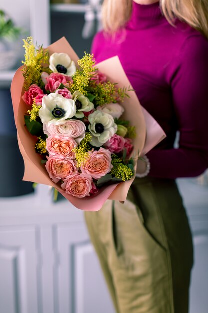 Schöner Blumenstrauß aus verschiedenen Blumen in der Hand des jungen Mannes. bunte Farbmischblume.