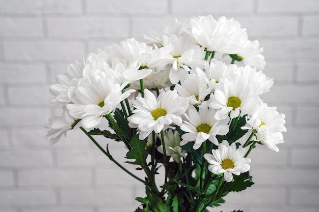 Schöner Blumenstrauß aus weißen Gänseblümchen auf dem Hintergrund einer Ziegelwand in der Nähe