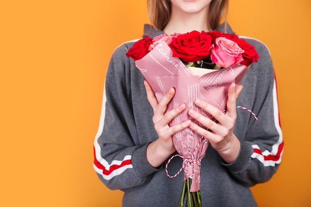 Schöner Blumenstrauß der Nahaufnahme mit Rosen auf Frauenhänden auf gelbem Hintergrundflorist, der schönen Blumenstrauß schafft