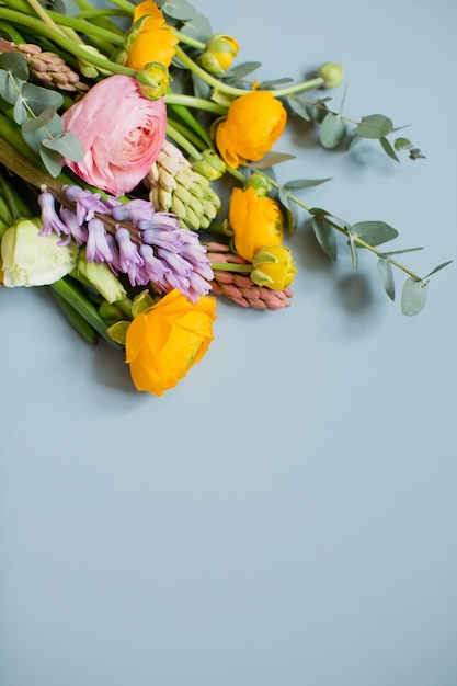 Schöner Blumenstrauß mit orangefarbenen und rosa Ranunkeln, Eukalyptus und Hyazinthe auf blauem Hintergrund Blumen auf blauem Hintergrund mit Platz für Text