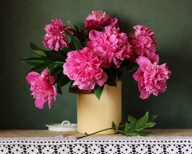 Schöner Blumenstrauß von rosa Pfingstrosen auf dem Tisch mit einer Spitzentischdecke. Gartenblumen