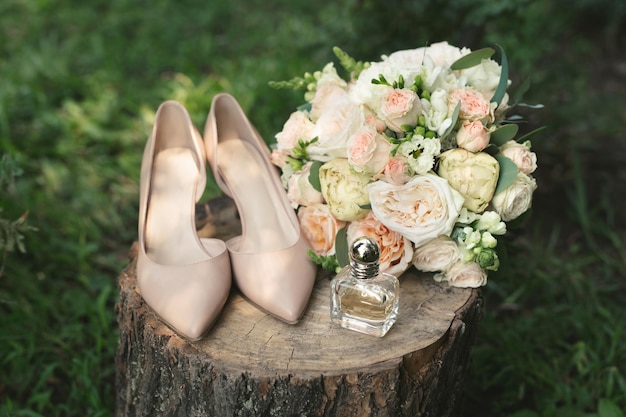 Schöner Brautstrauß aus weißen Rosen auf einem Holzstumpf. Stilvolle, Lederschuhe Braut beige. Hochzeit im Vintage-Stil