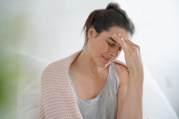 Schöner Brunette im Bett mit schlimmen Kopfschmerzen