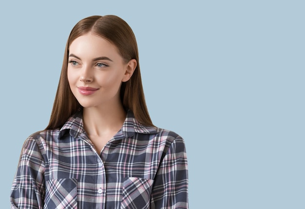 Foto schöner brunette im natürlichen porträt des karokleides. farbiger hintergrund. blau