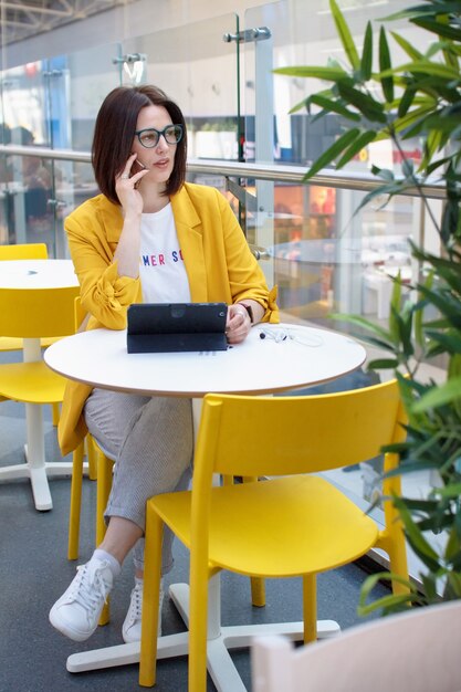 Schöner Brunette in einer gelben Jacke am Telefon,