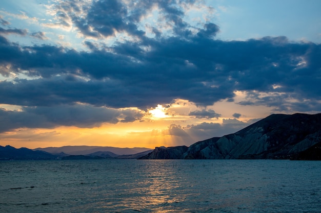 Schöner bunter Sonnenaufgang am Meer mit dramatischen Wolken und Sonnenschein