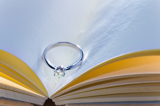 schöner Diamantring auf leerem geöffnetem Buch im kühlen und warmen Farbton
