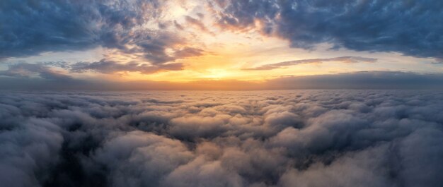 Schöner dramatischer Sonnenuntergangshimmel über flauschigen Wolken am frühen Morgen. Drohnenansicht.