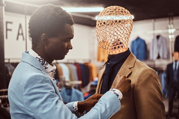 Schöner, elegant gekleideter afroamerikanischer Mann, der in einem klassischen Herrenbekleidungsgeschäft arbeitet.