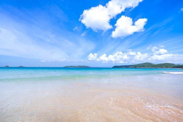 Schöner erstaunlicher goldfarbener Sandstrand mit weichen Wellen, die mit sonnigem blauem Himmel isoliert werden.