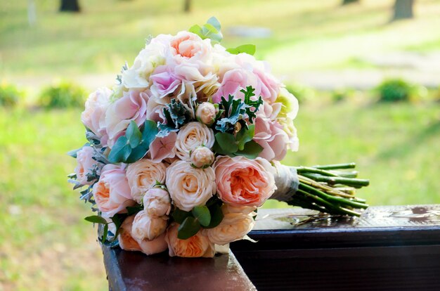 Schöner feierlicher Brautstrauß einer Braut aus Rosen und Eukalyptus liegt auf den Holzschienen