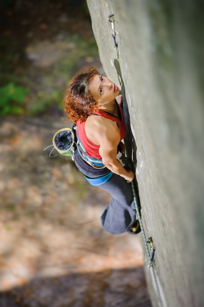 Schöner Frauenbergsteiger, der steilen Felsen mit Seil klettert