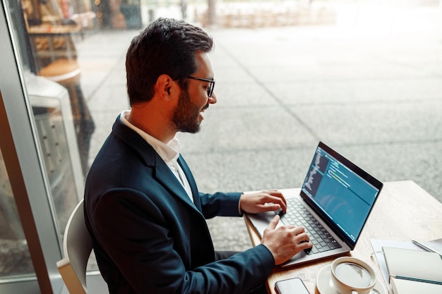 Schöner freiberuflicher Entwicklerprogrammierer mit Brille, der im Café an einem Projekt arbeitet