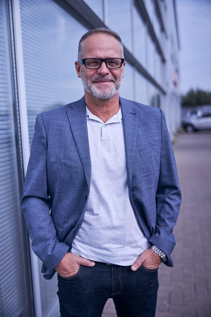 Foto schöner gentleman mit brille, der in die kamera schaut und lächelt, während er zeit im freien verbringt