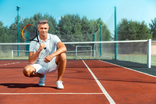 Schöner grauhaariger Mann hält Tennisschläger