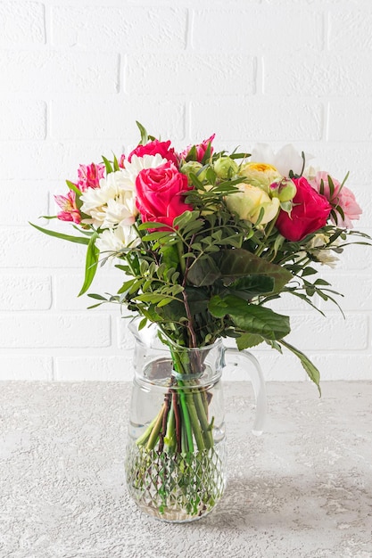 Schöner großer Strauß heller Blumen in einer Glasvase auf grauem Zementhintergrund das Konzept eines Urlaubs und eines Geschenks