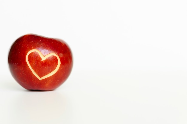 Schöner heller saftiger reifer roter Apfel mit einem herzförmigen Ausschnitt, lokalisiert auf einem weißen Hintergrund. Platz für Text