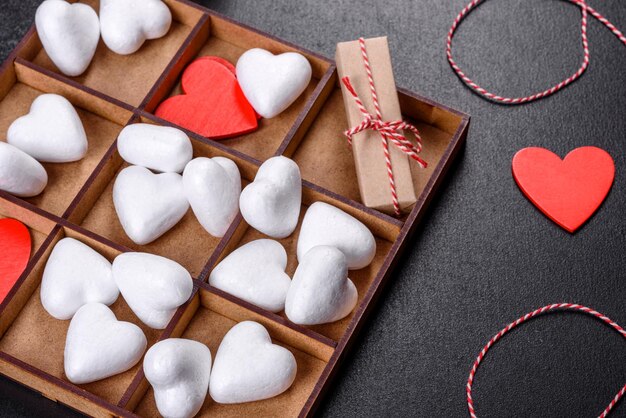 Schöner Hintergrund mit weißen und roten Herzen auf einem dunklen Tisch. Vorbereitung auf den Valentinstag