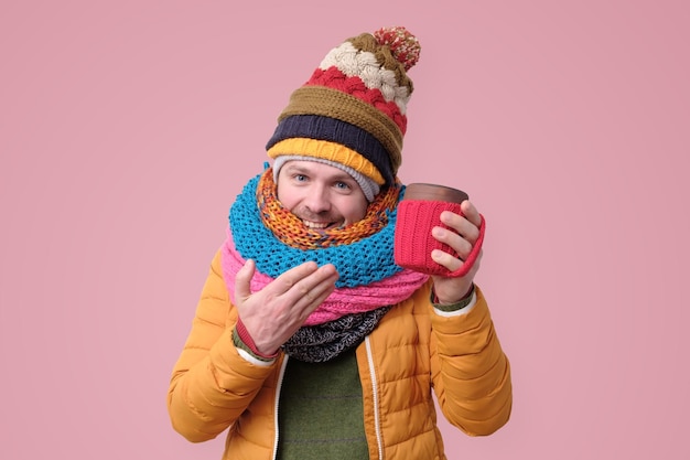 Schöner Hipster-Mann mit Hutschal hält Tasse mit heißem Kaffee oder Tee