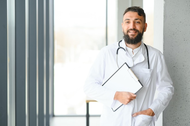 Schöner hispanischer Arzt mit Stethoskop in der Klinik mit einem fröhlichen und kühlen Lächeln im Gesicht Glückliche Person