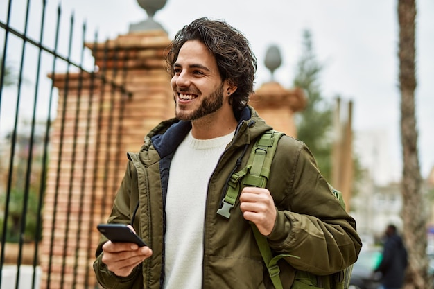 Schöner hispanischer Mann mit Smartphone in der Stadt