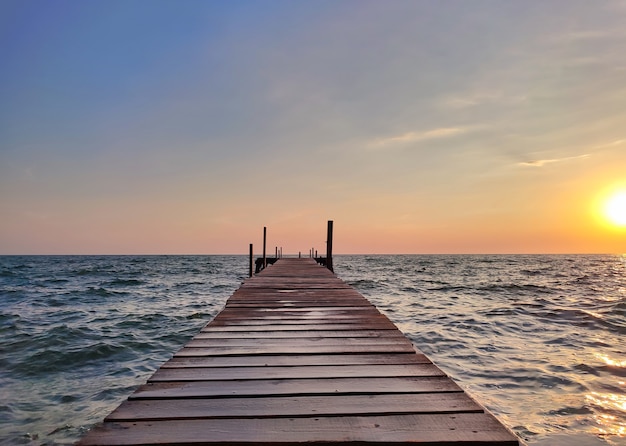 Schöner hölzerner Angelpier bei Sonnenuntergang auf dem Meer