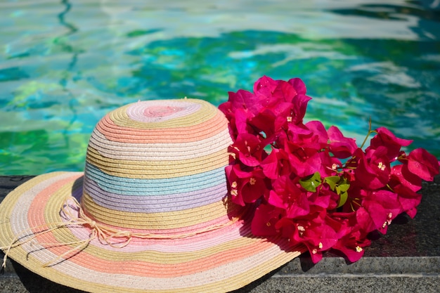 Schöner Hut und Blumen am Pool. Seeurlaub.