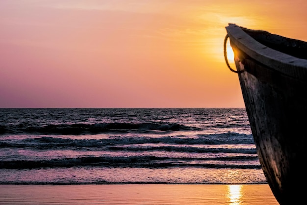 Schöner indischer Strand mit Dämmerungsfarbe während des Sonnenuntergangs und einem Fischerboot im Vordergrund