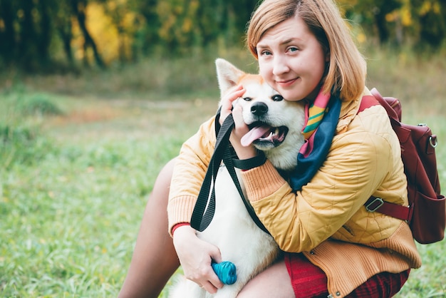 Schöner Ingwer-Husky-Hund, der mit Mädchen in den Herbstfarben spielt. Gefühlsporträt von Frau und foxy Hund Nahaufnahme. Mädchen spielt mit weißem rotem Husky im Park an der frischen Luft. Gehendes Haustier mit Besitzer im Freien.