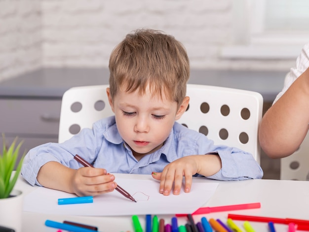 Schöner Junge, der Bild mit Bleistift im konzentrierten Jungen der Klasse zeichnet