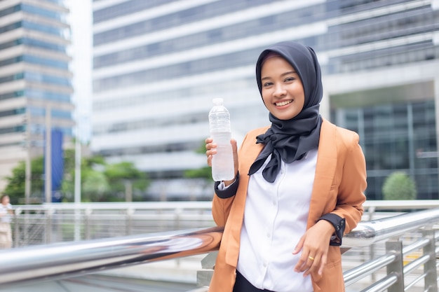 Schöner junger asiatischer Moslem mit Tafelwasser.