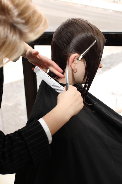 Schöner junger Friseur, der der Kundin im Salon einen neuen Haarschnitt gibt