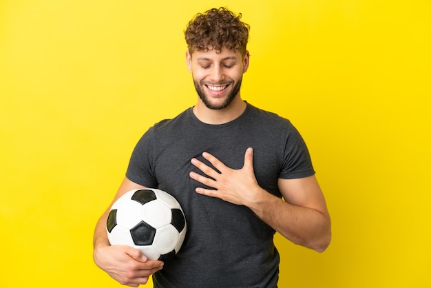 Schöner junger Fußballspieler Mann isoliert auf gelbem Hintergrund lächelt viel