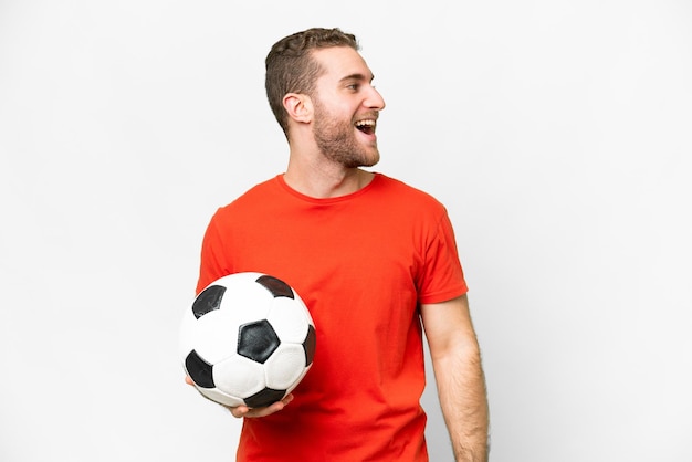 Schöner junger Fußballspieler mit isoliertem weißem Hintergrund, der in Seitenlage lacht