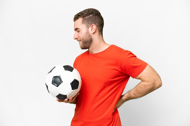 Schöner junger Fußballspieler mit isoliertem weißem Hintergrund, der unter Rückenschmerzen leidet, weil er sich Mühe gegeben hat