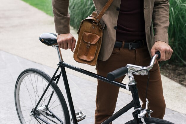 Schöner junger Geschäftsmann mit seinem modernen Fahrrad.