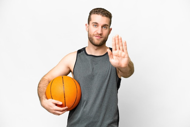Schöner junger Mann, der Basketball vor isoliertem weißem Hintergrund spielt und eine Stopp-Geste macht