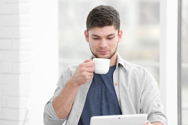 Schöner junger Mann, der zu Hause Kaffee trinkt