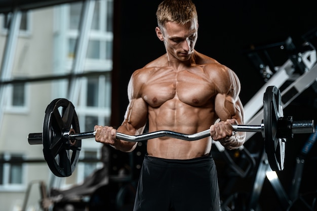 Schöner junger Mann des Modells, der im Fitnessstudio arbeitet