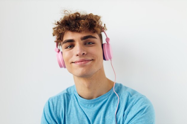 Schöner junger Mann in blauen T-Shirts rosa Kopfhörer Mode isolierter Hintergrund