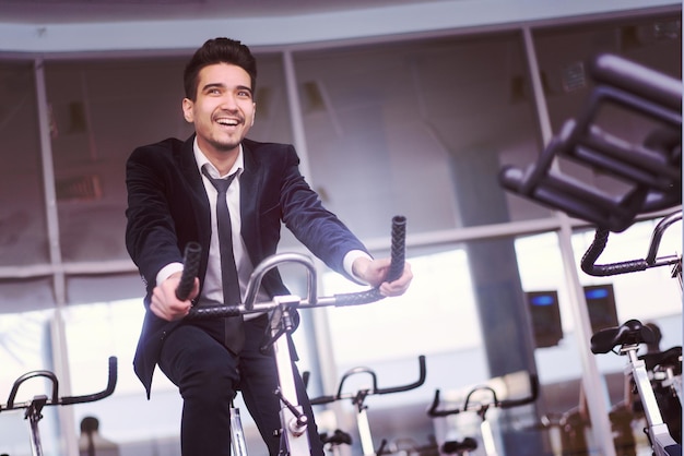 Schöner junger Mann in einem schwarzen Anzug, weißem Hemd und Krawattentraining im Fitnessstudio