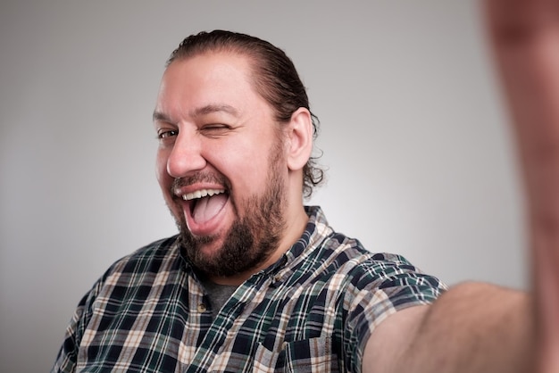 Foto schöner junger mann in freizeitkleidung macht selfie auf grauem hintergrund er hat ein glückliches gesicht, das mit den zähnen lächelt